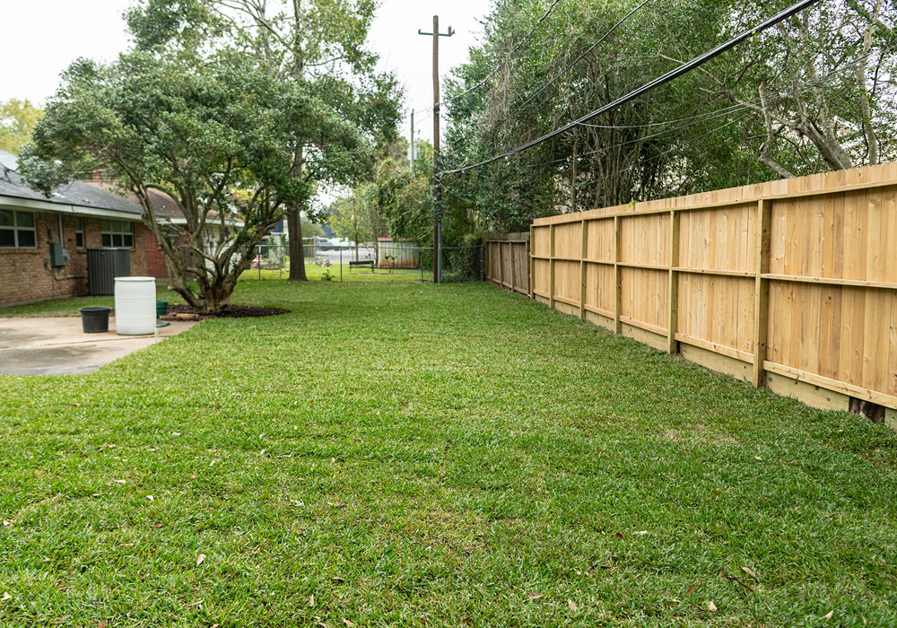 residential home with beautiful landscape in back yard and wooden fence