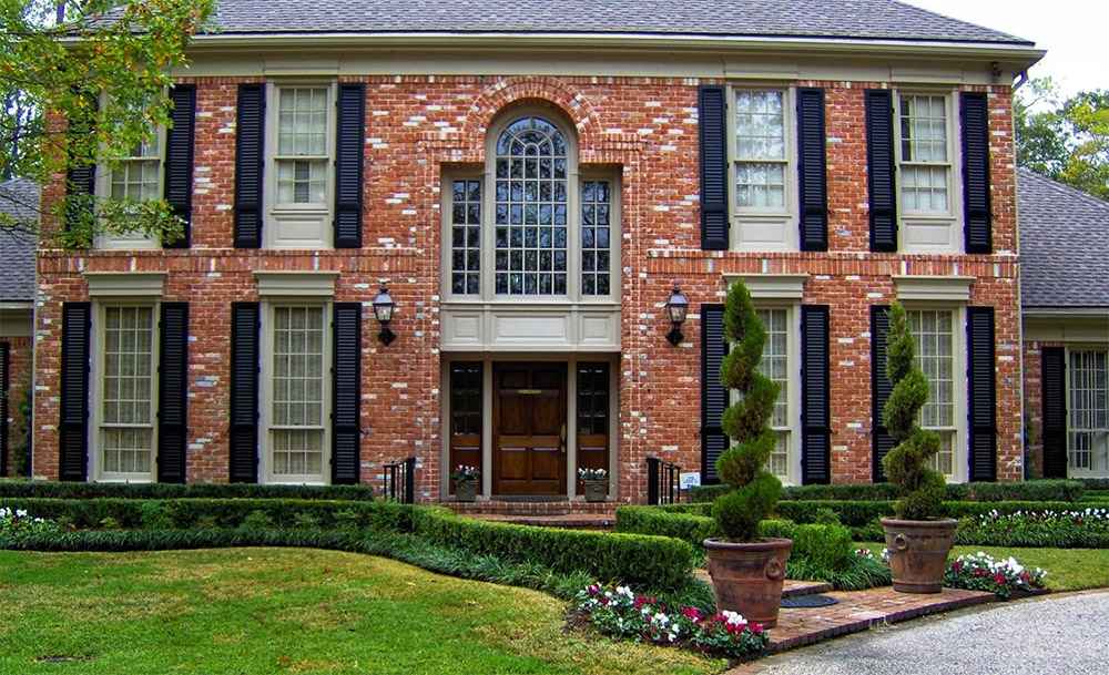 Brick house with a wide front yard landscape, showcasing charm and a welcoming vibe in Houston, TX