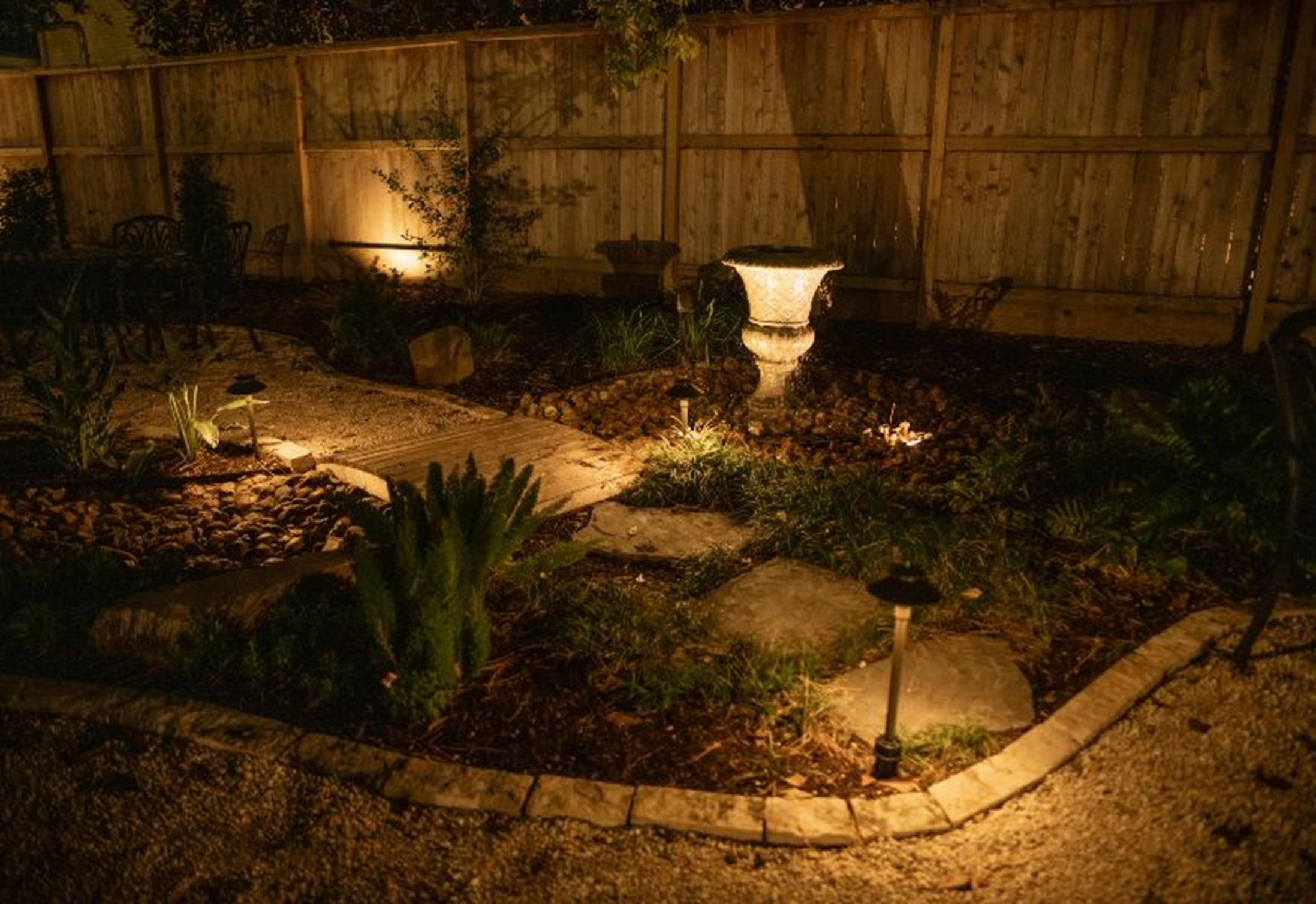 Landscape lighting installation illuminating a garden pathway and plants at night in Houston, TX