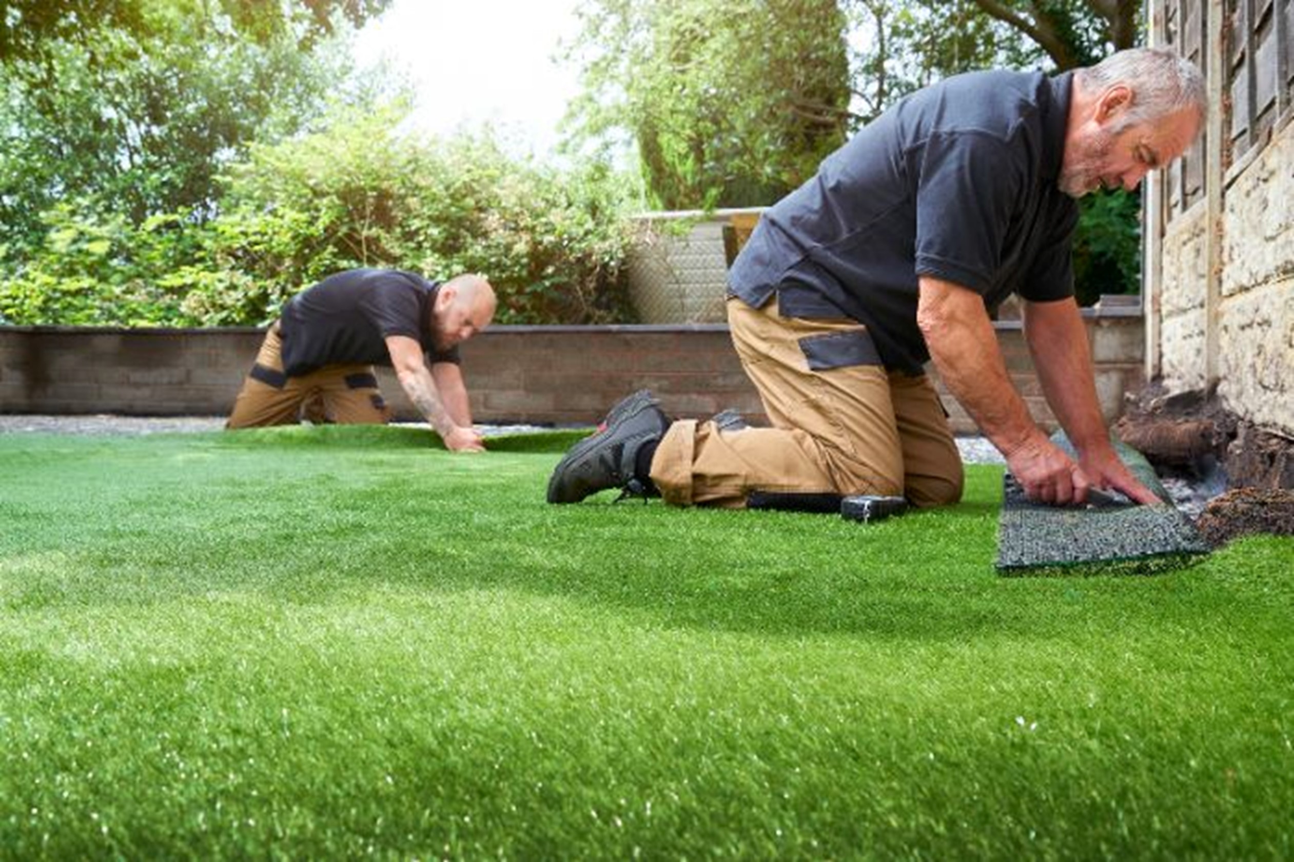 Men installing synthetic grass by Absolute Lawn Care & Landscaping