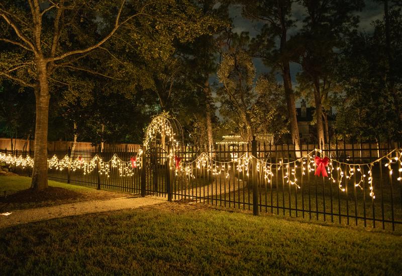 Glowing Christmas lights installed on a black metal fence in Houston, TX
