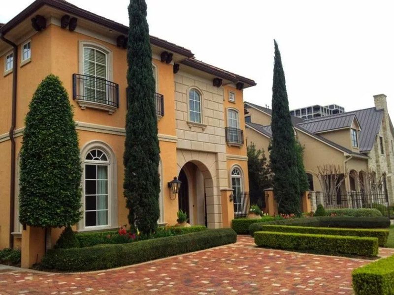 Elegant landscape design featuring manicured hedges and tall sculpted evergreens in Houston, TX