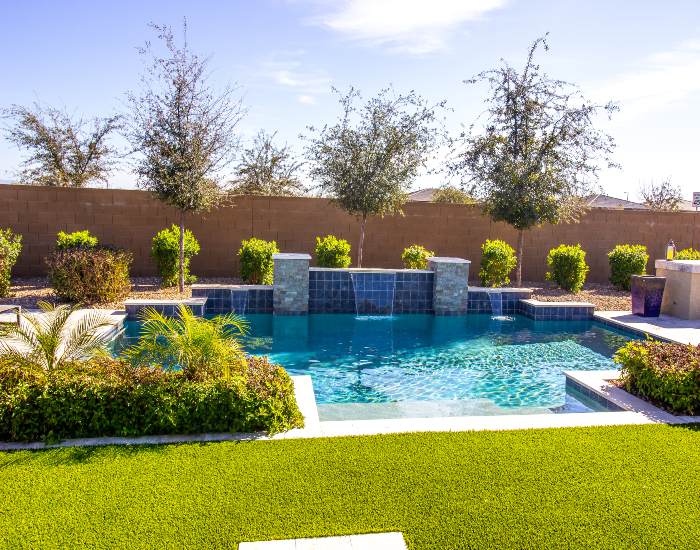 Backyard pool landscaping design featuring stone accents and small plants in Houston, TX