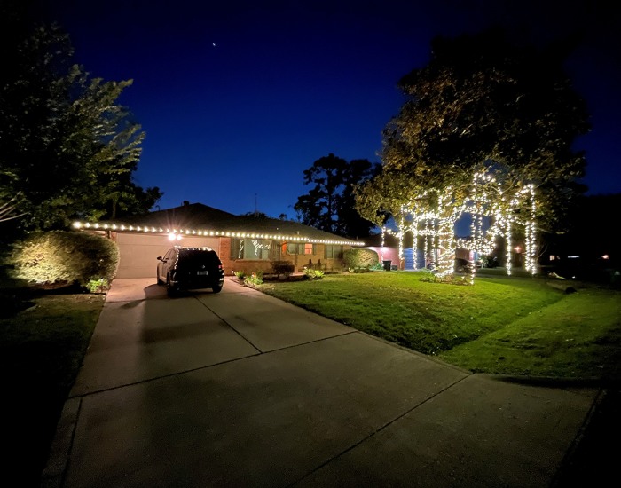 Beautiful Christmas lights brighten a home’s exterior and front‑yard trees in Houston, TX