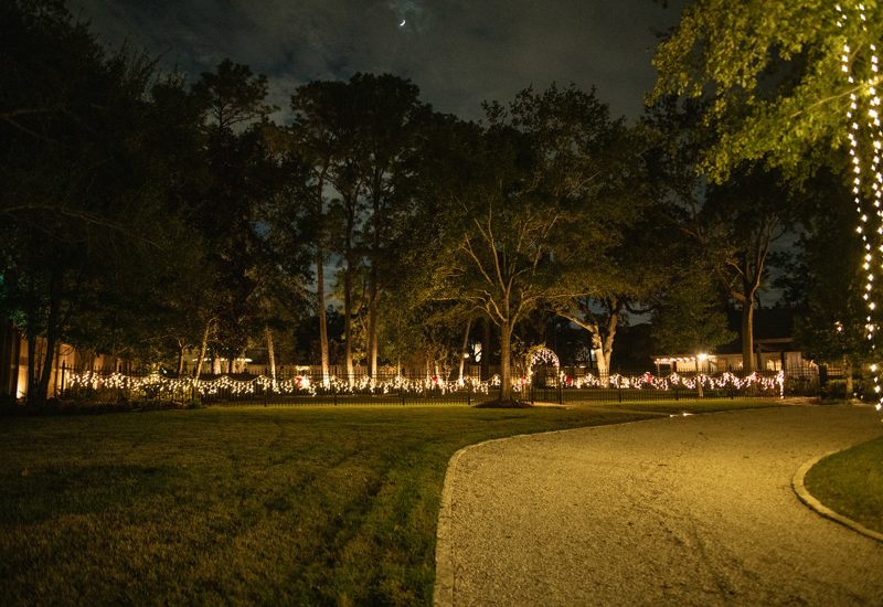 Wide view of an outdoor Christmas lights installed on a fence in Houston, TX