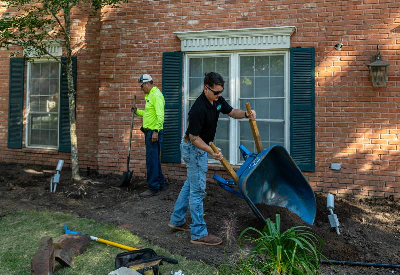 A worker is providing a mulching solution in a residential garden in Houston, TX