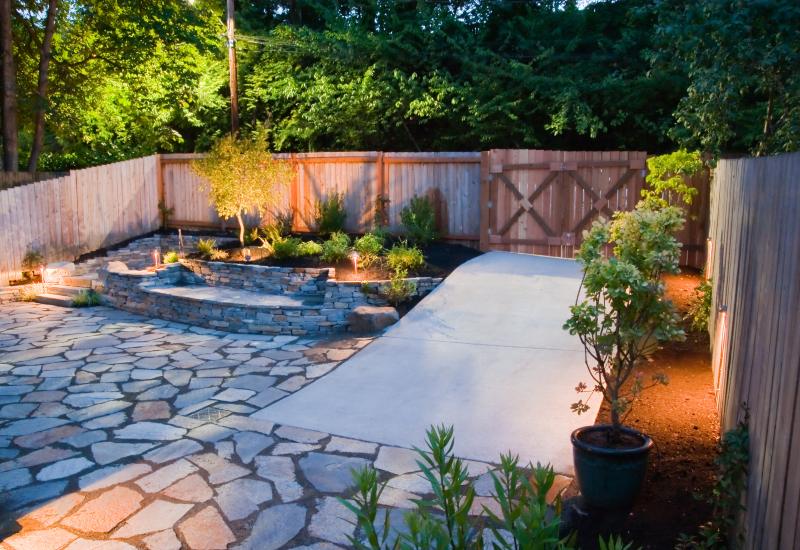 Modern backyard makeover design featuring stone pavers, small plants, and lights in Houston, TX