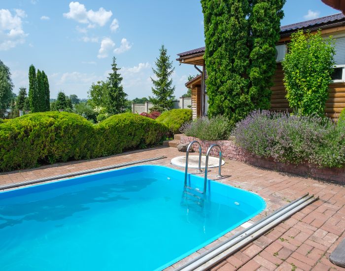 Residential pool installation featuring trimmed green bushes and a paver patio in Houston, TX