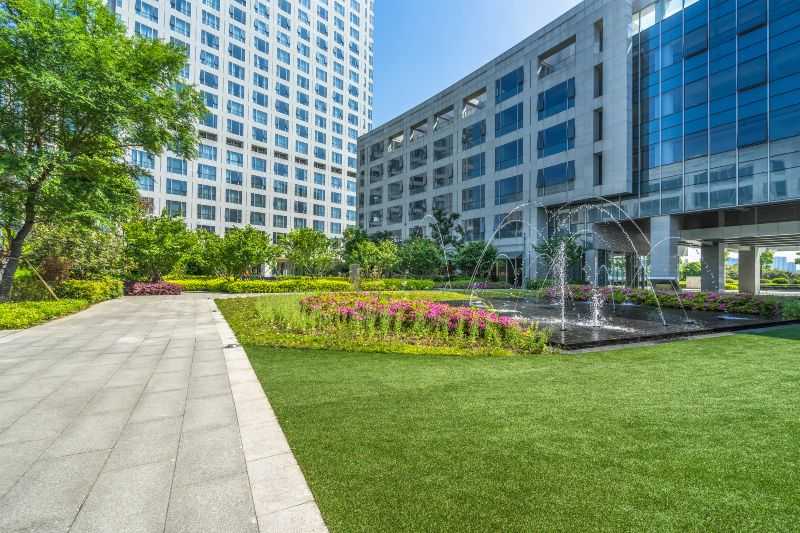Corporate plaza with fountains, green lawn, and offices in Houston, TX