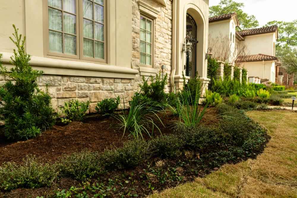 Front yard landscaping with stone beds and shrubs at luxury home in Houston, TX