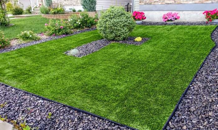Artificial turf lawn with decorative gravel borders and landscaped plants, in Houston, TX